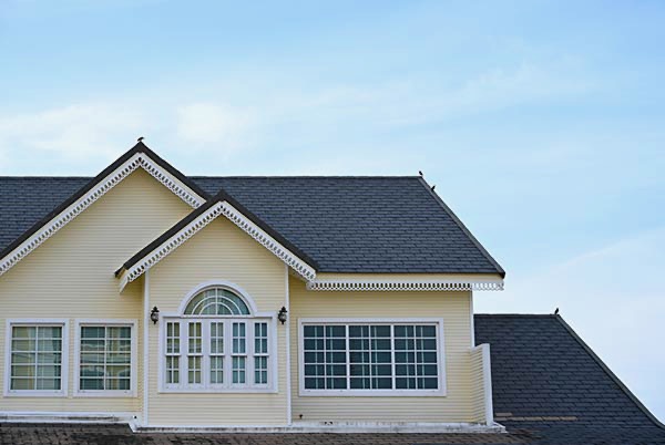 Grey shingle roofing on pale yellow home